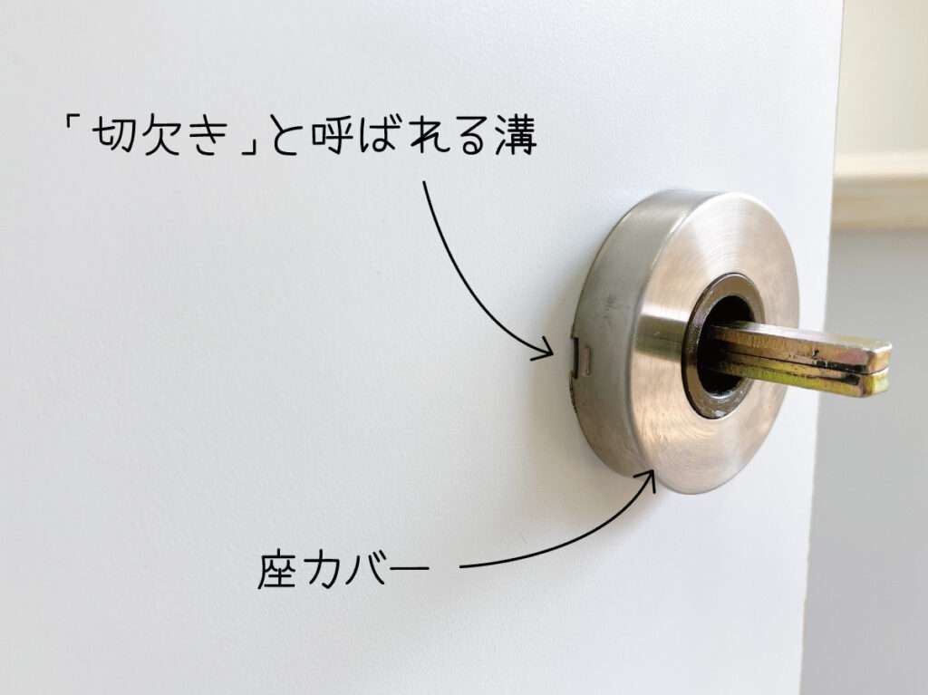 シール壁紙でドアをおしゃれにリメイクする。レバーハンドルの切欠きにマイナスドライバーを入れ、座カバーを外す。